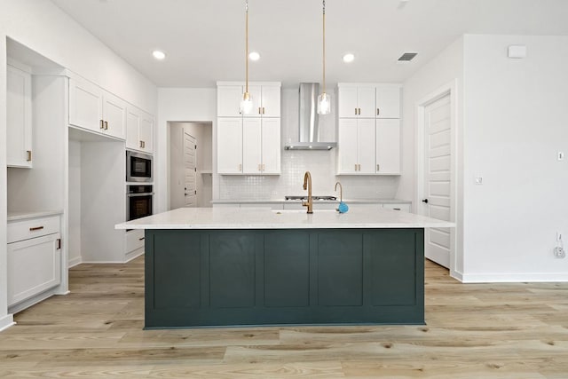 kitchen featuring white cabinets, appliances with stainless steel finishes, wall chimney range hood, and visible vents
