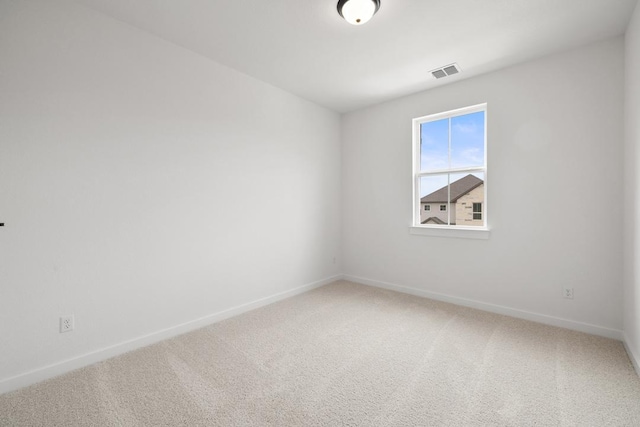 unfurnished room with visible vents, light colored carpet, and baseboards