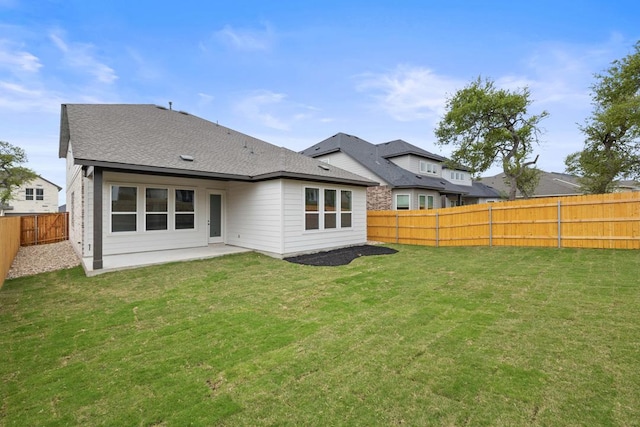 back of house with a yard, a fenced backyard, a shingled roof, and a patio area