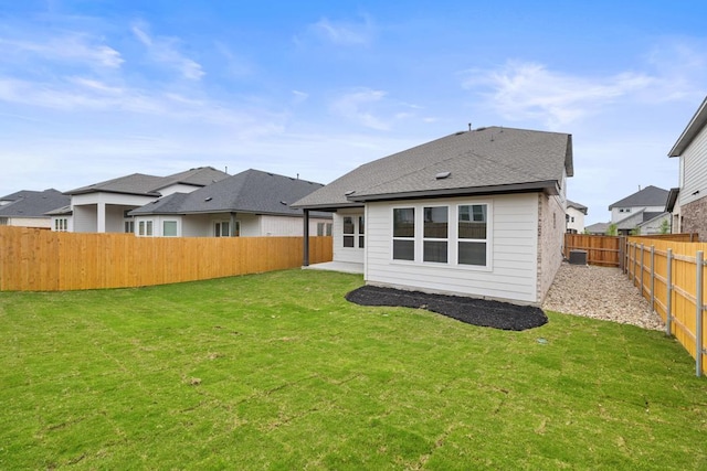 rear view of house featuring a yard, a fenced backyard, a patio, a residential view, and roof with shingles