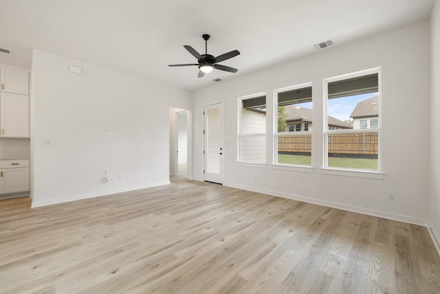 unfurnished living room with light wood-style floors, baseboards, visible vents, and ceiling fan