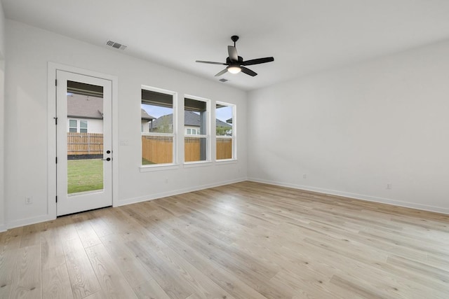 empty room featuring light wood-type flooring, baseboards, a ceiling fan, and visible vents