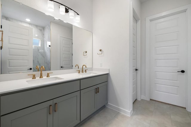 full bath featuring a sink, tile patterned flooring, a marble finish shower, and double vanity