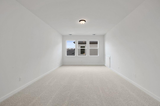 unfurnished room with light carpet and baseboards