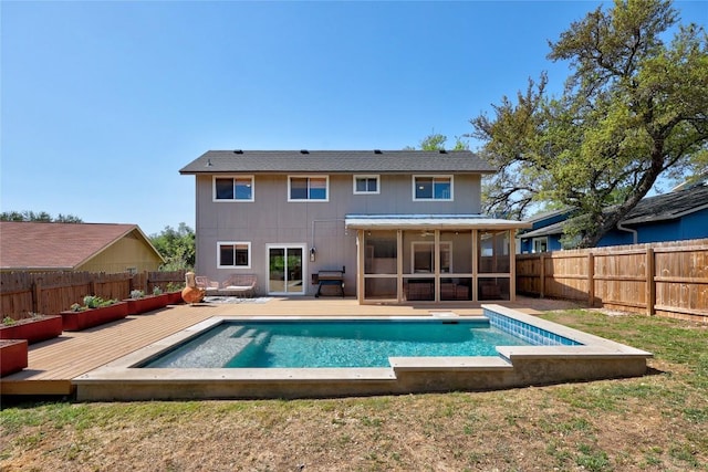 rear view of property with a sunroom, a fenced in pool, a wooden deck, and a fenced backyard