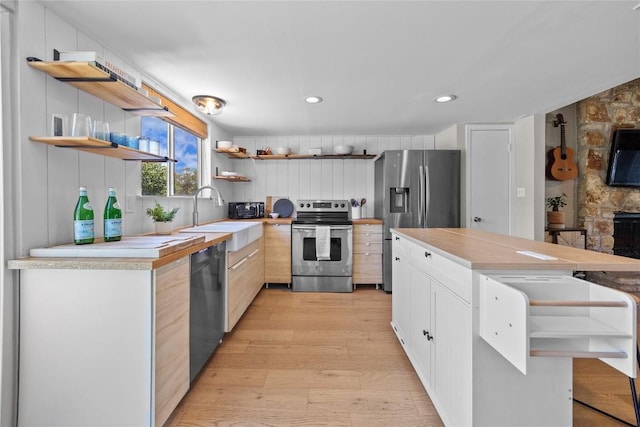 kitchen featuring appliances with stainless steel finishes, recessed lighting, a sink, open shelves, and light wood-type flooring