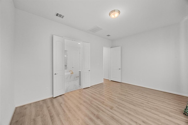 409 Dycus Bnd, Liberty Hill, TX 78642 - unfurnished bedroom featuring light wood-type flooring, baseboards, and connected bathroom