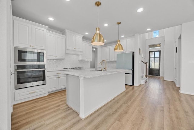 409 Dycus Bnd, Liberty Hill, TX 78642 - kitchen with freestanding refrigerator, a sink, white cabinets, gas cooktop, and light wood-style floors