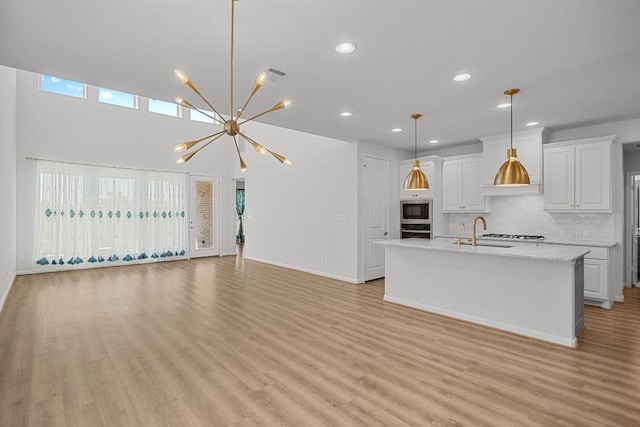 409 Dycus Bnd, Liberty Hill, TX 78642 - kitchen with stainless steel appliances, light countertops, a sink, light wood-type flooring, and a chandelier