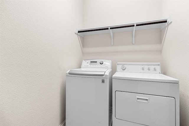 laundry area featuring a textured wall, washer and clothes dryer, and laundry area