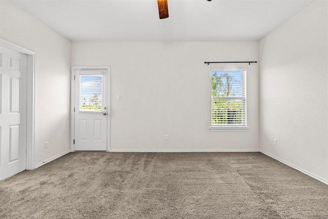 carpeted spare room with ceiling fan and baseboards