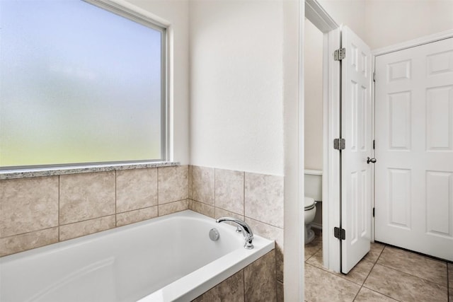 bathroom featuring a bath, toilet, and tile patterned flooring