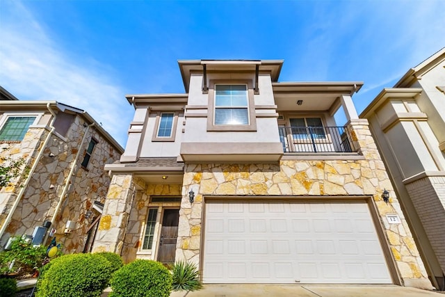 view of front of home with stone siding, an attached garage, a balcony, and concrete driveway