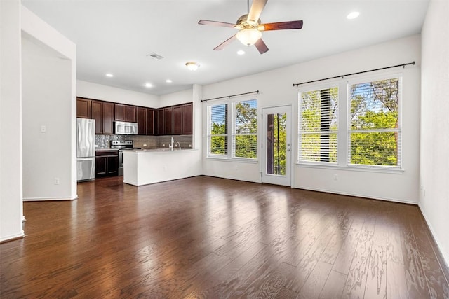 unfurnished living room with a ceiling fan, a sink, baseboards, dark wood-type flooring, and visible vents