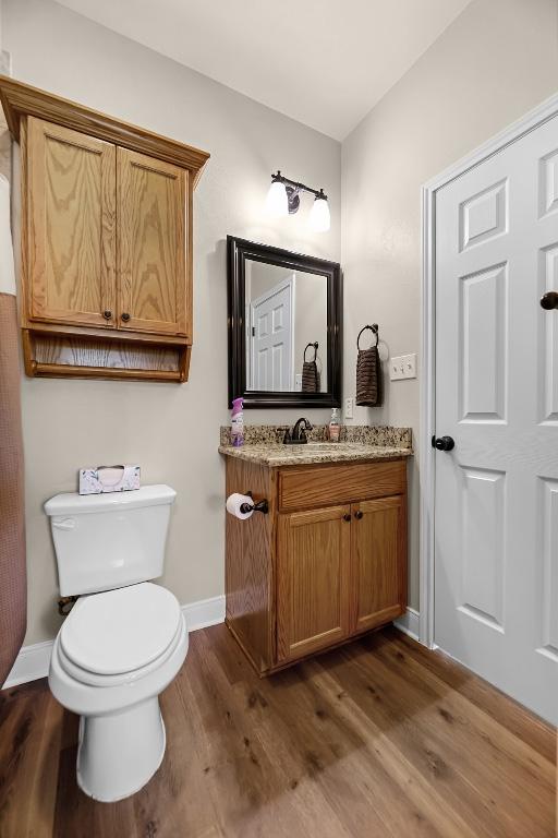 125 Brahman Ct, Bastrop, TX 78602 - bathroom featuring toilet, wood finished floors, vanity, and baseboards