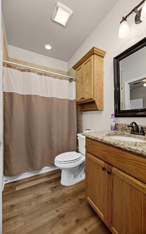 125 Brahman Ct, Bastrop, TX 78602 - full bath with toilet, vanity, wood finished floors, a shower with shower curtain, and recessed lighting