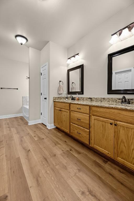 125 Brahman Ct, Bastrop, TX 78602 - bathroom with double vanity, wood finished floors, a tub, and baseboards