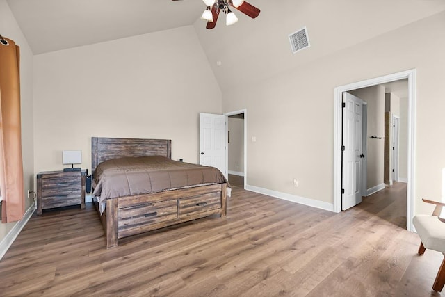 bedroom with visible vents, baseboards, high vaulted ceiling, and wood finished floors