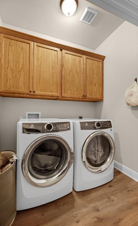 125 Brahman Ct, Bastrop, TX 78602 - laundry area with cabinet space, separate washer and dryer, wood finished floors, and baseboards