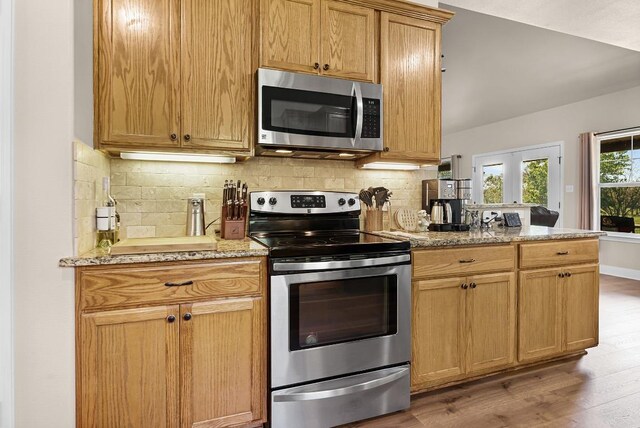 125 Brahman Ct, Bastrop, TX 78602 - kitchen featuring stainless steel appliances, light wood finished floors, backsplash, and light stone counters