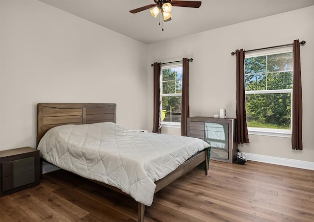 125 Brahman Ct, Bastrop, TX 78602 - bedroom featuring multiple windows, wood finished floors, baseboards, and a ceiling fan