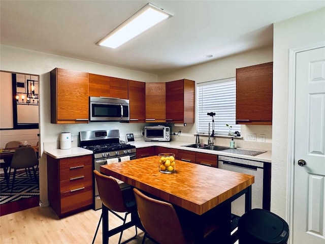 16903 Isle Of Man Rd, Pflugerville, TX 78660 - kitchen featuring stainless steel appliances, a sink, a kitchen bar, light wood-style flooring, and butcher block counters