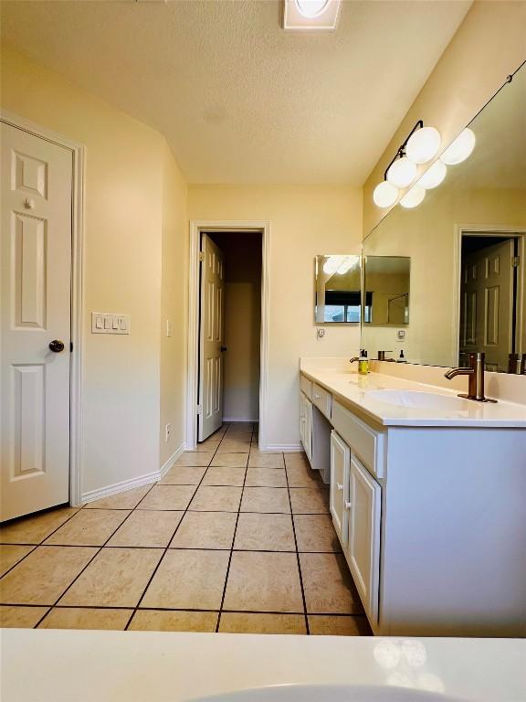 16903 Isle Of Man Rd, Pflugerville, TX 78660 - full bathroom with double vanity, tile patterned flooring, baseboards, and a textured ceiling