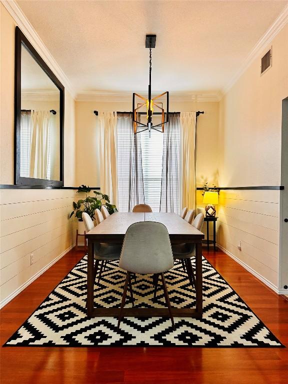 16903 Isle Of Man Rd, Pflugerville, TX 78660 - dining area with a chandelier, healthy amount of natural light, crown molding, wood finished floors, and wooden walls