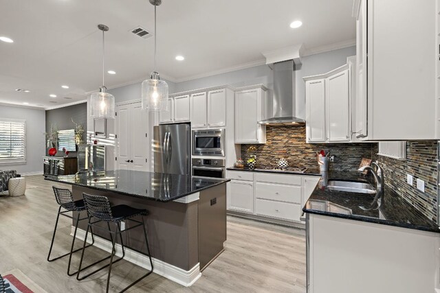 1013 Highknoll Ln, Georgetown, TX 78628 - kitchen featuring stainless steel appliances, wall chimney range hood, ornamental molding, white cabinetry, and dark stone countertops