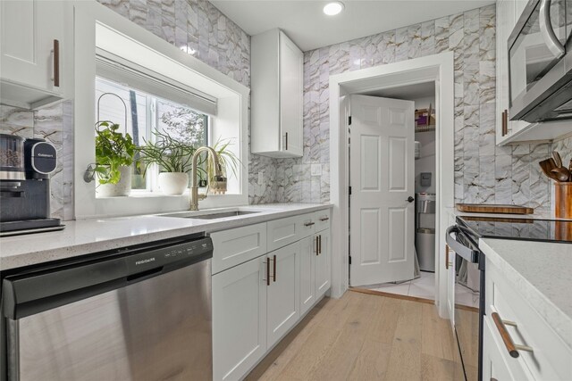 1616 Webberville Rd Unit A, Austin, TX 78721 - kitchen featuring stainless steel appliances, white cabinets, light wood-type flooring, light stone countertops, and decorative backsplash