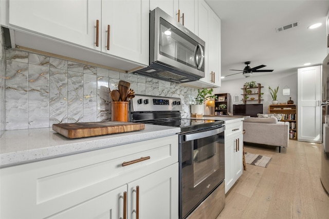 1616 Webberville Rd Unit A, Austin, TX 78721 - kitchen with stainless steel appliances, white cabinets, a ceiling fan, decorative backsplash, and open floor plan