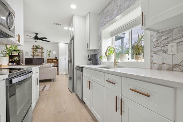 1616 Webberville Rd Unit A, Austin, TX 78721 - kitchen featuring stainless steel appliances, a ceiling fan, white cabinets, light wood-style flooring, and recessed lighting