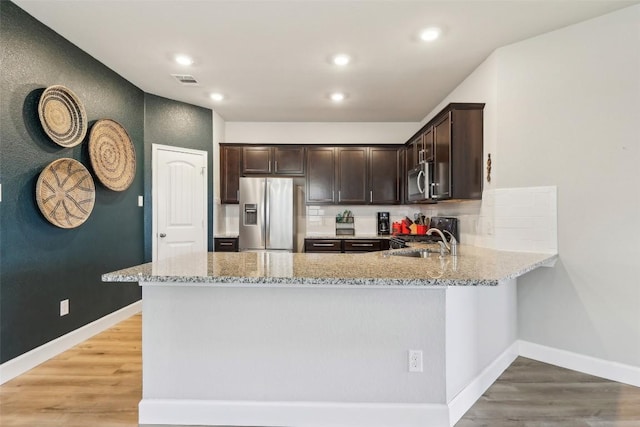 353 Cherry Laurel Ln, Kyle, TX 78640 - kitchen with stainless steel appliances, light stone countertops, a peninsula, dark brown cabinetry, and a sink