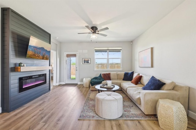 353 Cherry Laurel Ln, Kyle, TX 78640 - living room with wood finished floors, a glass covered fireplace, ceiling fan, and baseboards