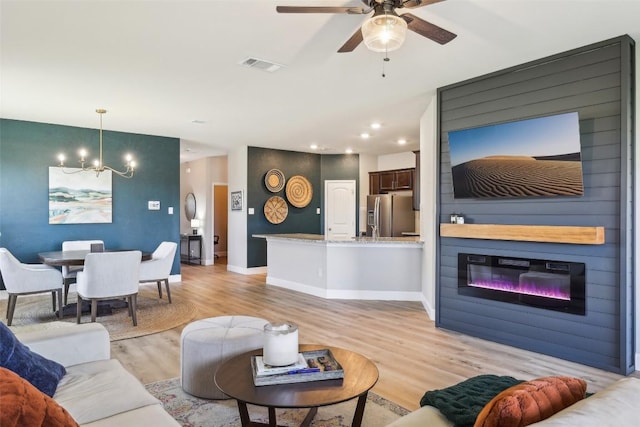 353 Cherry Laurel Ln, Kyle, TX 78640 - living area featuring light wood-style floors, a chandelier, a ceiling fan, recessed lighting, and a fireplace
