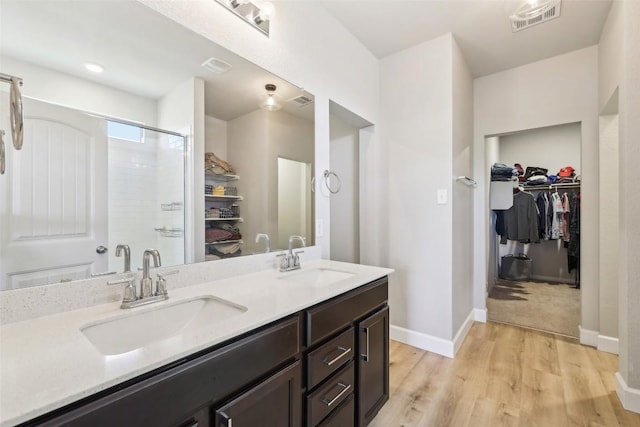 353 Cherry Laurel Ln, Kyle, TX 78640 - full bathroom featuring a spacious closet, double vanity, wood finished floors, a shower stall, and baseboards