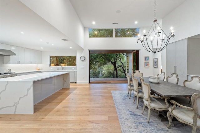 7 Rocky River Cv, West Lake Hills, TX 78746 - dining space featuring light wood finished floors, an inviting chandelier, a towering ceiling, and visible vents
