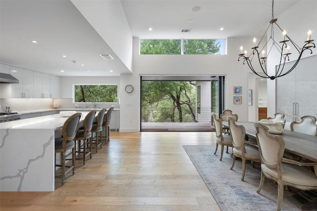 7 Rocky River Cv, West Lake Hills, TX 78746 - dining area with light wood-style floors, a high ceiling, an inviting chandelier, and visible vents