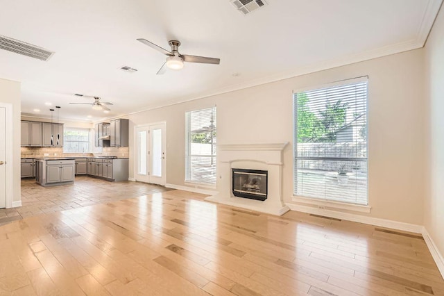 8404 Cahill Dr, Austin, TX 78729 - unfurnished living room with a ceiling fan, plenty of natural light, ornamental molding, baseboards, and light wood finished floors