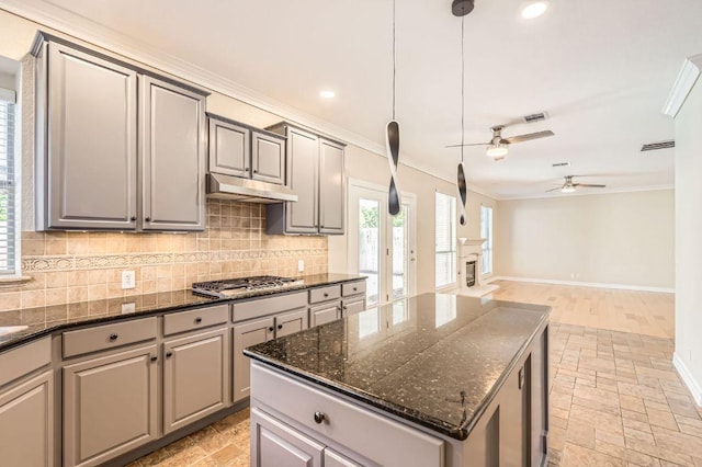 8404 Cahill Dr, Austin, TX 78729 - kitchen featuring stainless steel gas stovetop, backsplash, ornamental molding, under cabinet range hood, and gray cabinets