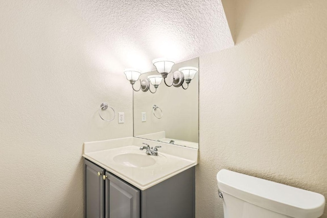 8404 Cahill Dr, Austin, TX 78729 - half bathroom featuring a chandelier, vanity, toilet, and a textured ceiling