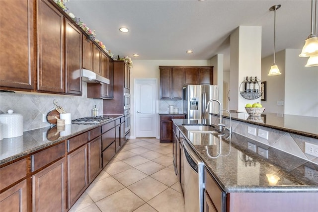 4829 Pyrenees Pass, Austin, TX 78738 - kitchen featuring stainless steel appliances, under cabinet range hood, tasteful backsplash, light tile patterned flooring, and pendant lighting