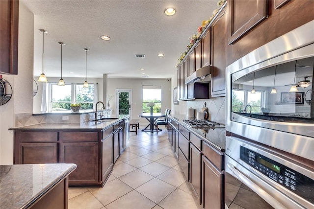 4829 Pyrenees Pass, Austin, TX 78738 - kitchen featuring appliances with stainless steel finishes, decorative backsplash, dark stone counters, recessed lighting, and pendant lighting