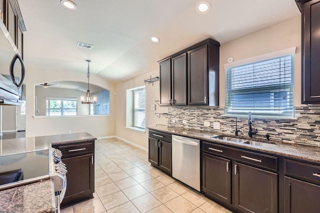 kitchen featuring appliances with stainless steel finishes, a notable chandelier, a sink, a healthy amount of sunlight, and decorative backsplash