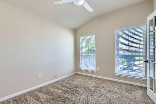 carpeted spare room with ceiling fan, baseboards, and vaulted ceiling