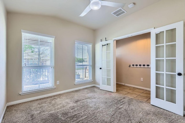spare room featuring tile patterned flooring, carpet flooring, french doors, visible vents, and ceiling fan