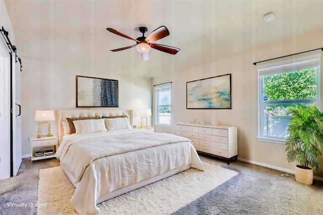 bedroom with a barn door, carpet flooring, baseboards, and ceiling fan