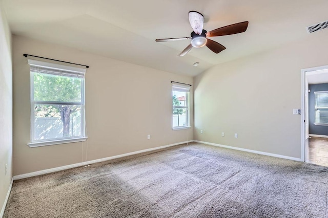 carpeted spare room featuring baseboards, visible vents, vaulted ceiling, and a ceiling fan