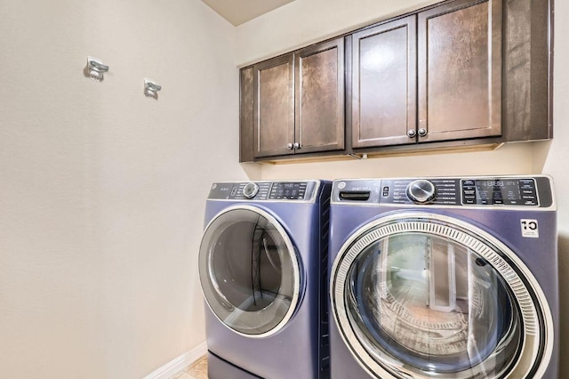 washroom with baseboards, washing machine and clothes dryer, and cabinet space
