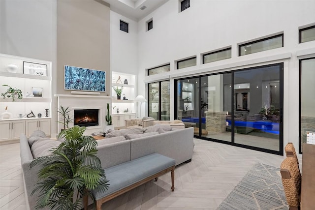 living room with a warm lit fireplace, visible vents, and a towering ceiling
